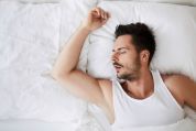 Unrasierter Mann in weissem Unterhemd liegt mit geöffneten Mund im Bett, von oben betrachtet Unrasierter Mann in weissem Unterhemd liegt mit geöffneten Mund im Bett, von oben betrachtet